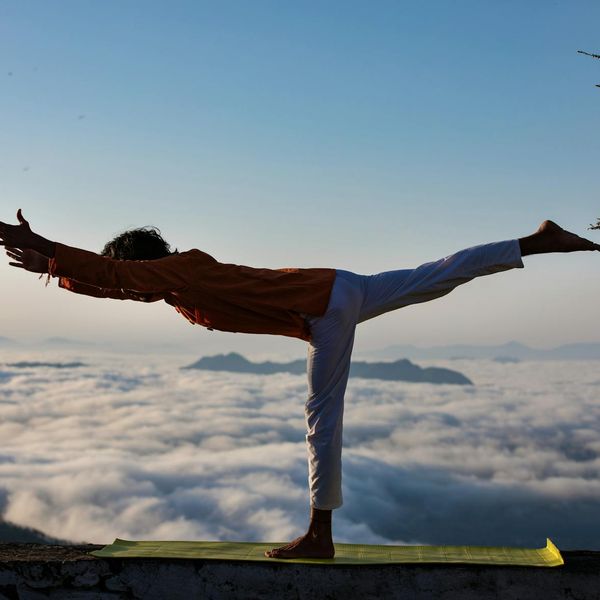 Man performing a warrior yoga pose outdoors with a beautiful landscape.
